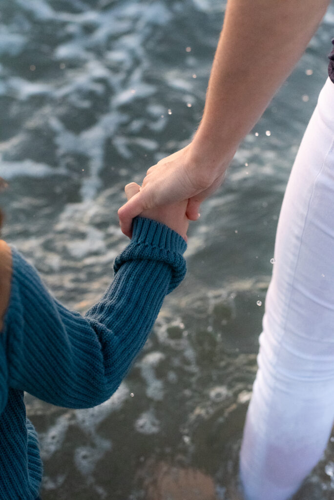 Mom and son holding hands with ocean spray between them