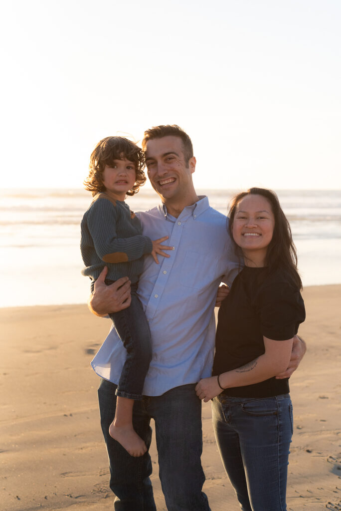 Family smiles on beach in Oceanside, CA
