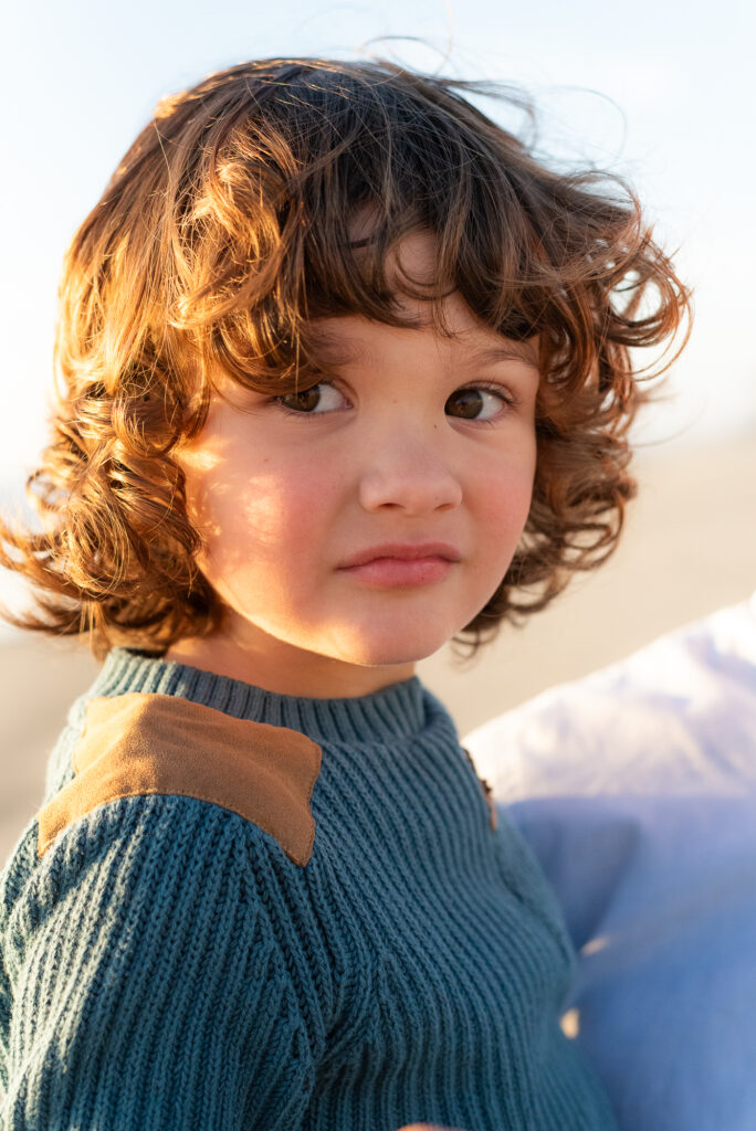 Portrait of young boy with curly hair during golden hour in Oceanside, CA