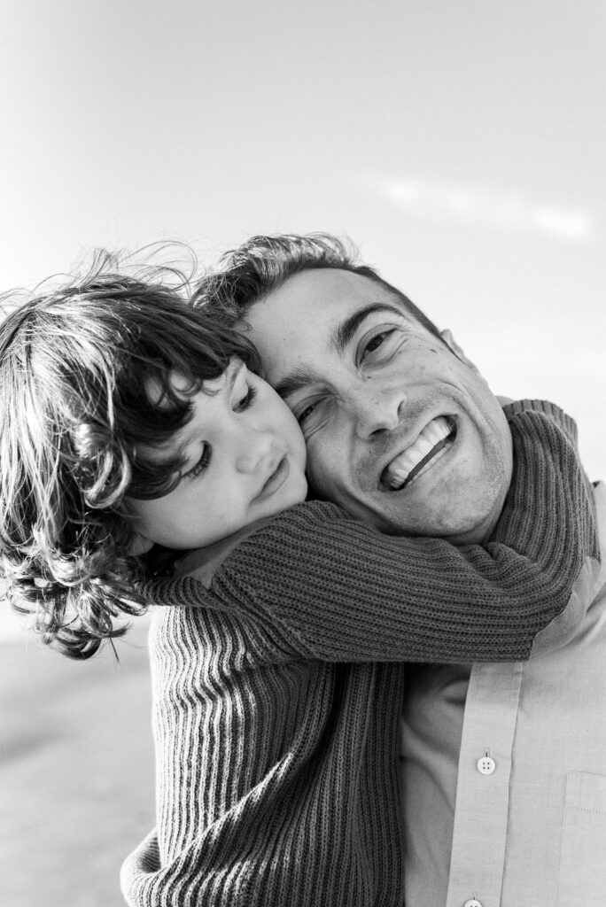 Portrait of young boy hugging his dad's neck tight