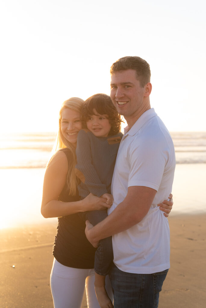 Golden hour photo of a family smiling at the beach in Oceanside, California