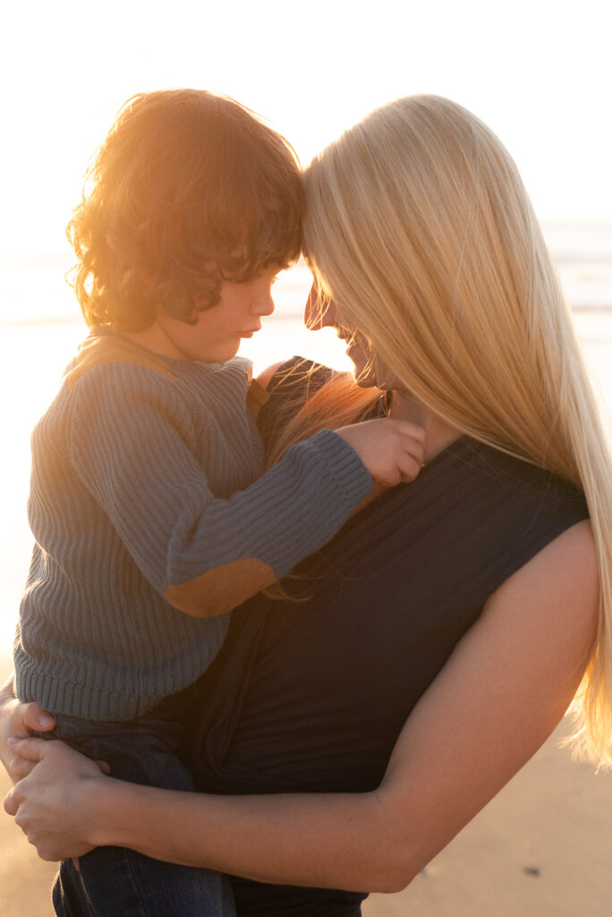 Golden hour photo of mom holding young son and touching foreheads during a family photography session