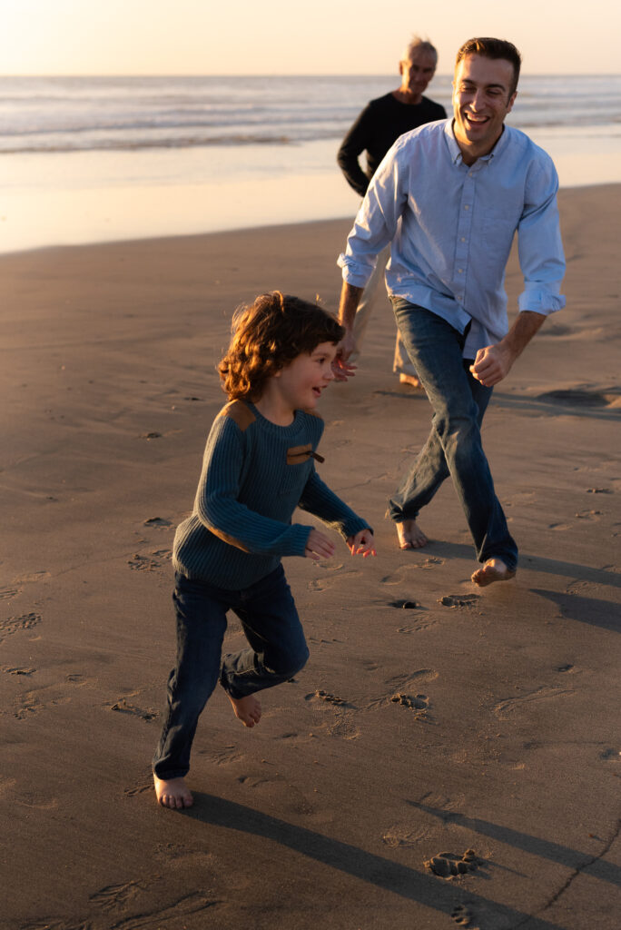 Dad chasing his son on the beach at sunset in Oceanside, California