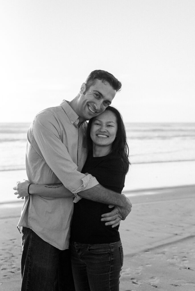 In love couple holds each other and smiles at Oceanside beach