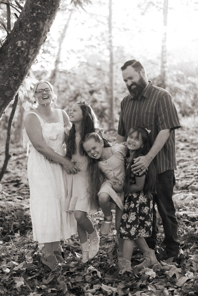 A soft black and white photograph of a family of five laughing together at Dinwiddie Preserve in Fallbrook, CA