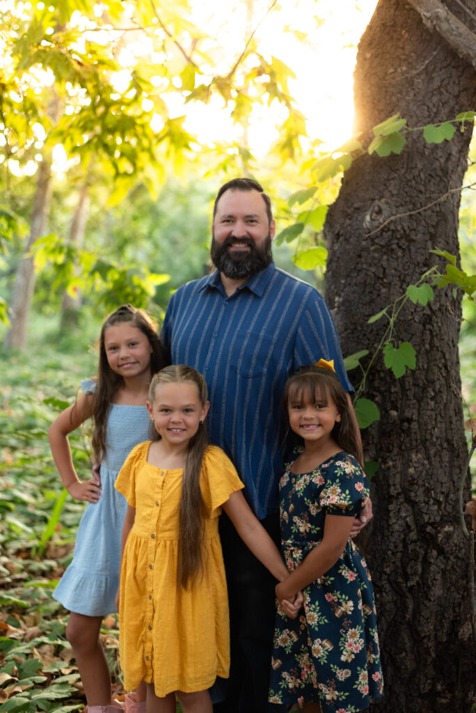 A dad and his three daughters pose in front of a vine wrapped oak tree at Dinwiddie Preserve, CA