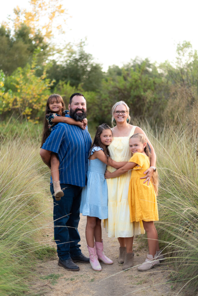 A family of five with three daughters poses in vibrant yellow and blue outfits at Dinwiddie Preserve in Fallbrook, CA
