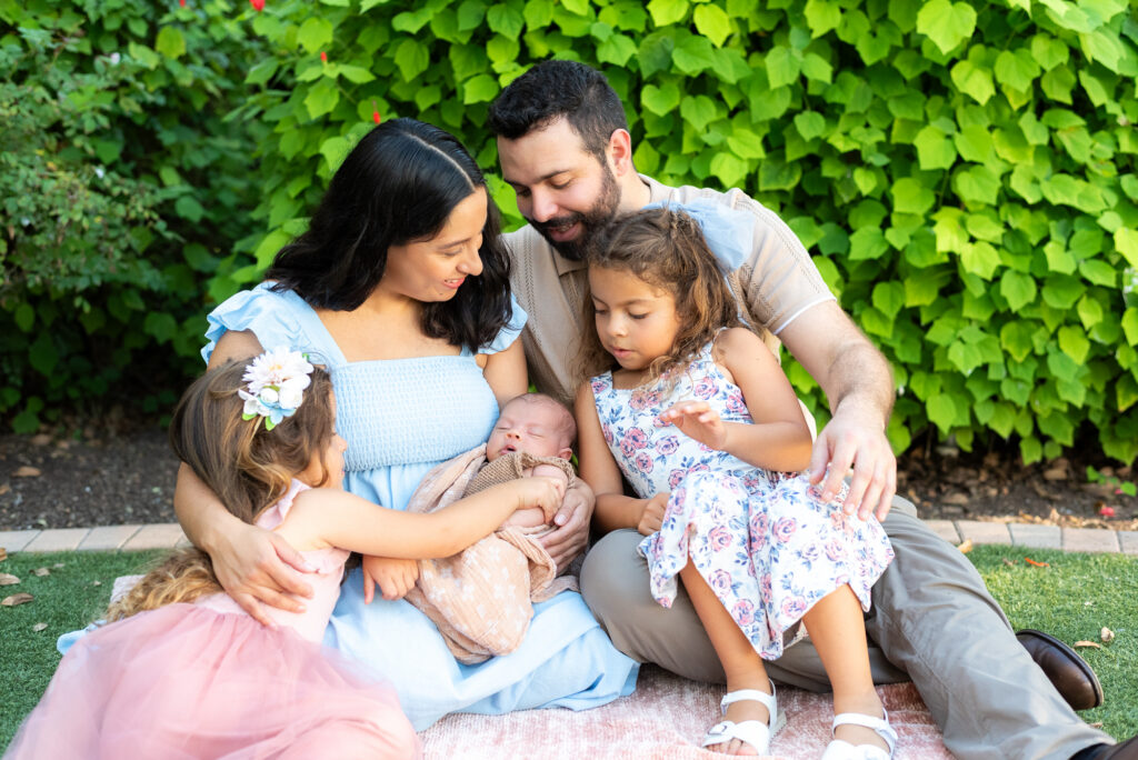 A family of 5 site and look down upon their newborn family member at Alta Vista Botanical Garden