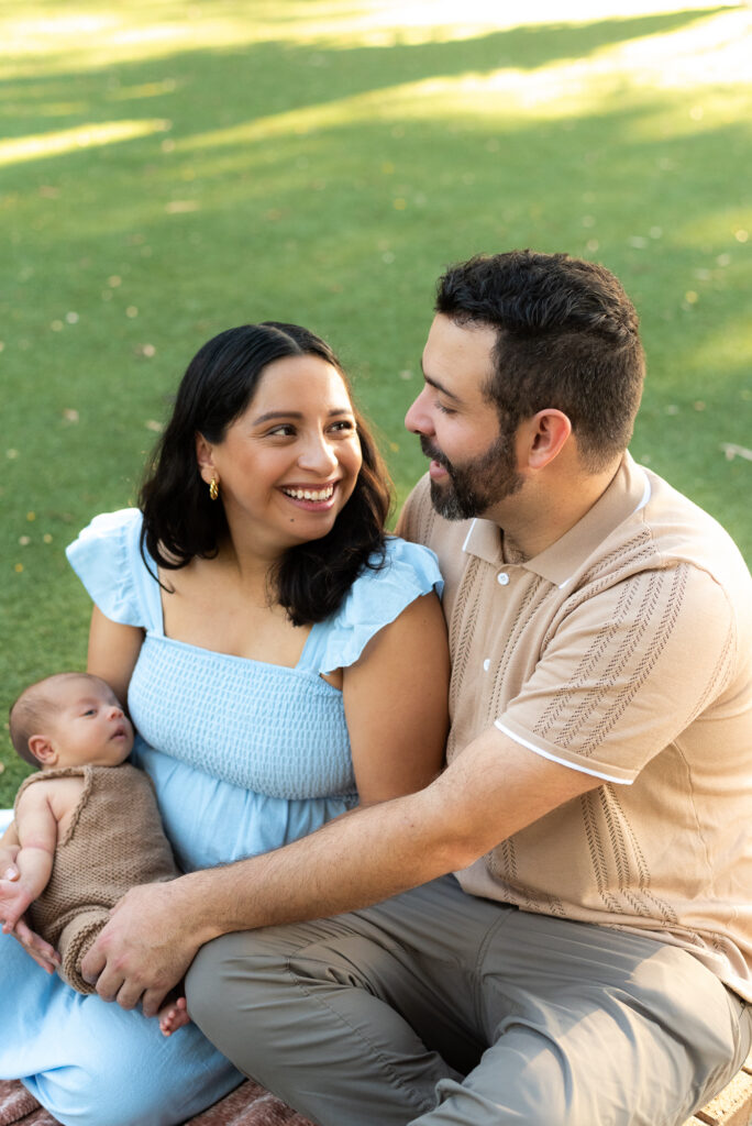 Loving parents smile at each other while holding their newborn baby