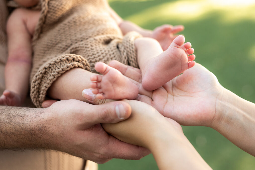 A close up of a newborns feet held by his parents hands at Alta Vista Botanical Garden