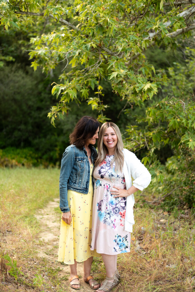 Adult daughter and mother wear spring dresses and pose together at Marian Bear Park in San Diego