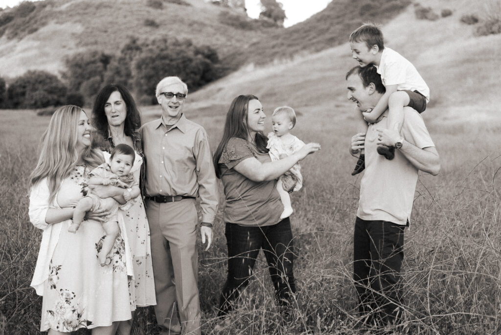 Black and white photo of extended family have fun in a field at Marian Bear park in San Diego