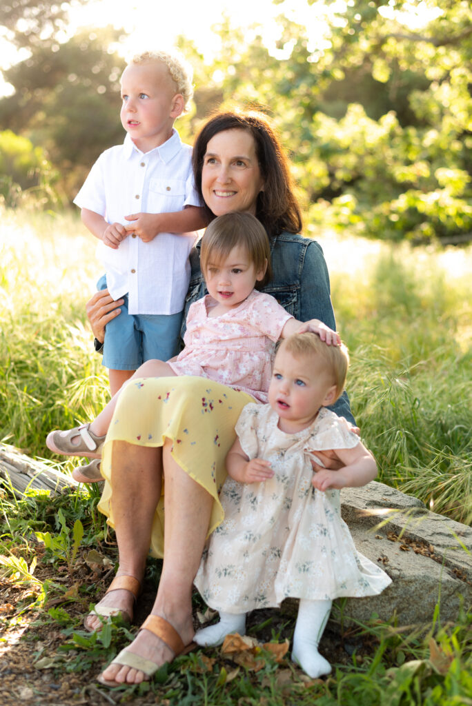 Grandmother with her 3 grandchildren in spring field at Marian Bear Park in San Diego