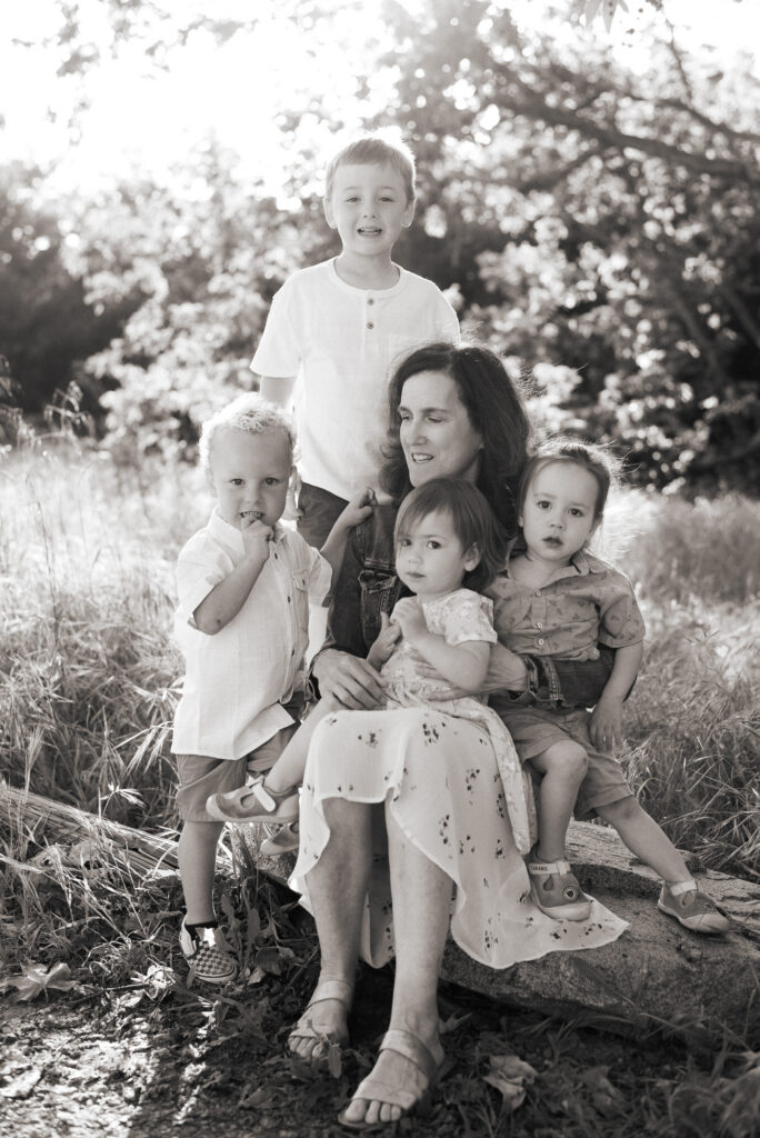 Black and white image of a grandmother sitting and holding her four grandchildren with golden light in the background