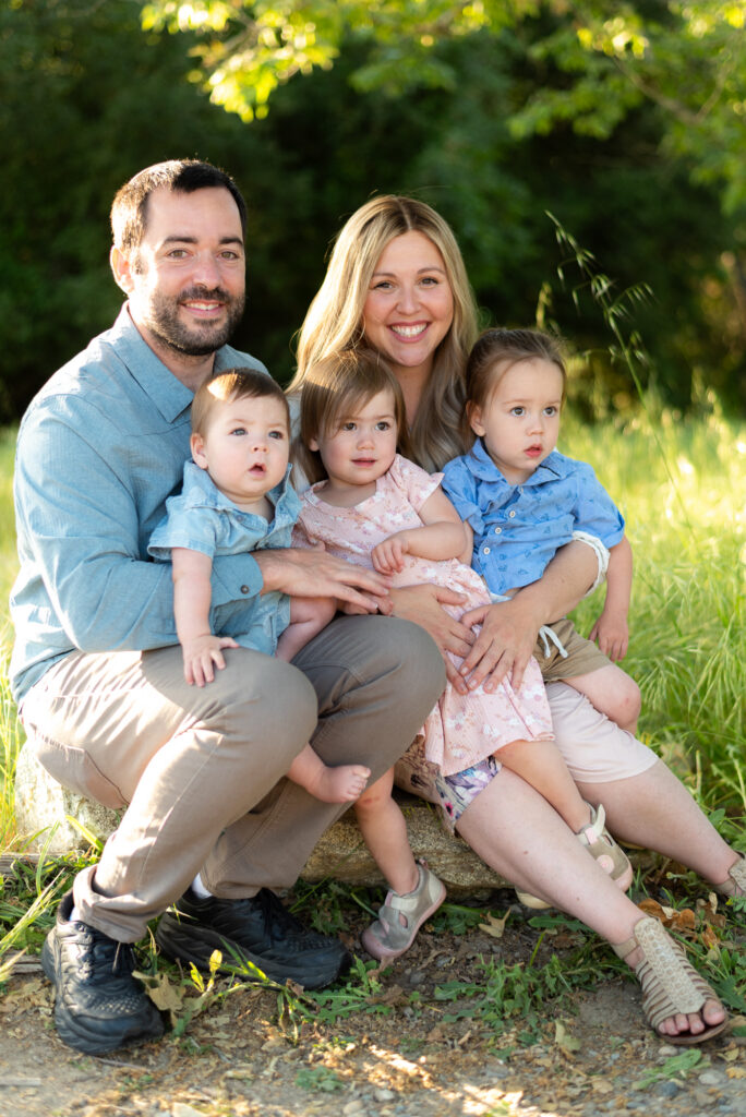 Family of five with three under 3 sit on a log in a spring field a Marian Bear Park, San Diego