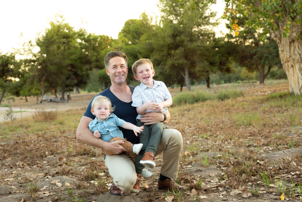 Dad kneeling with two young sons laughing