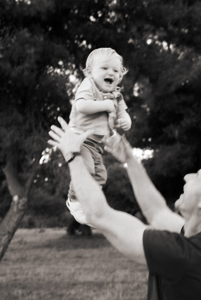 Toddler boy being thrown in the air by his father, a black and white blurred photo