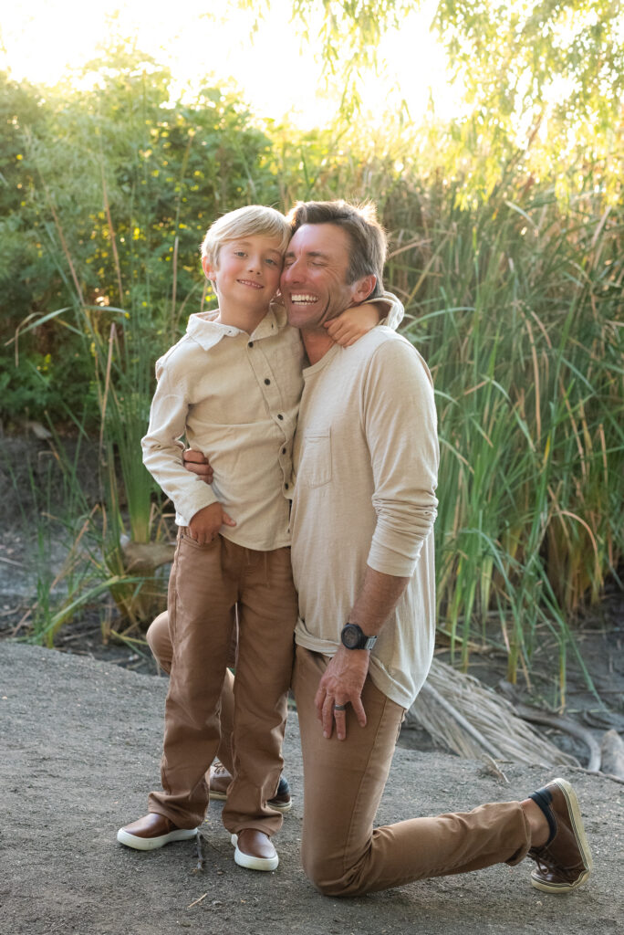 Dad hugs his son during their San Diego golden hour family photography session at Guajome Park, Oceanside