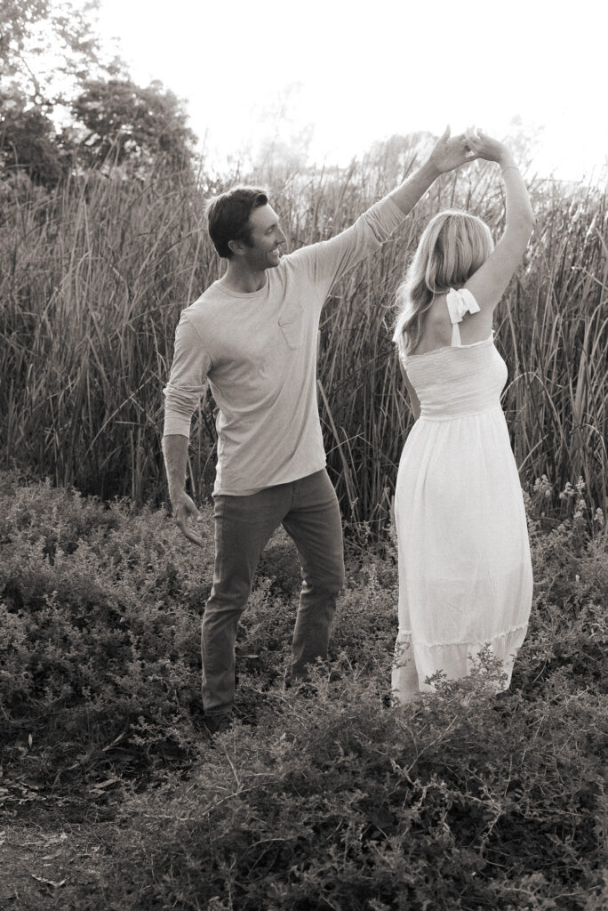 black and white photo of a husband spinning his wife during a romantic moment during their San Diego golden hour family photography session at Guajome Park, Oceanside
