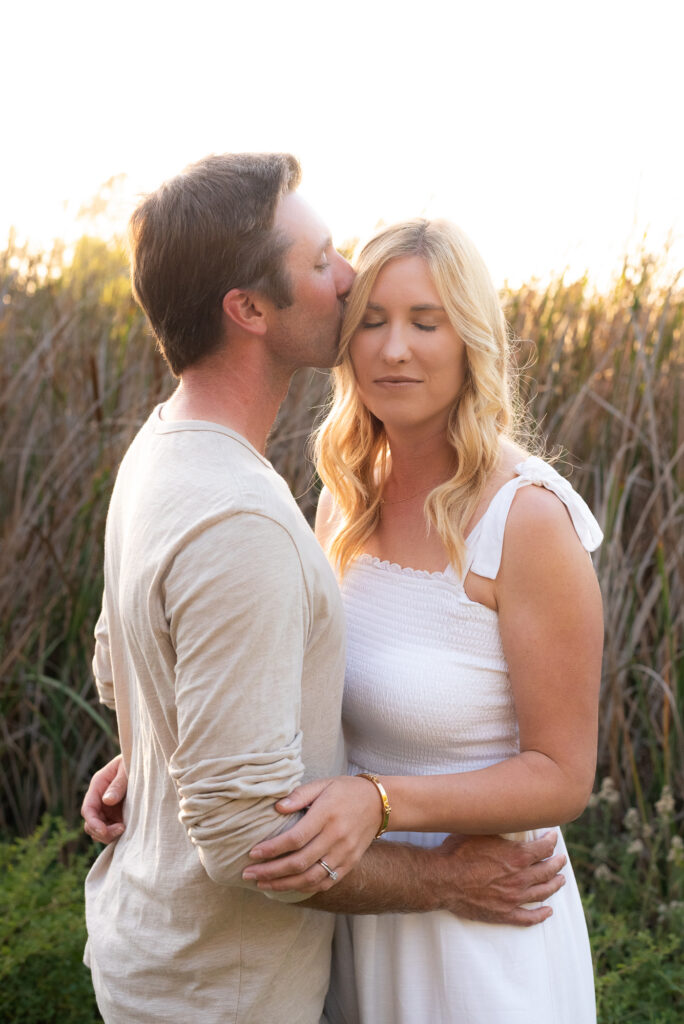 Husband and wife have a romantic moment during their San Diego golden hour family photography session at Guajome Park, Oceanside