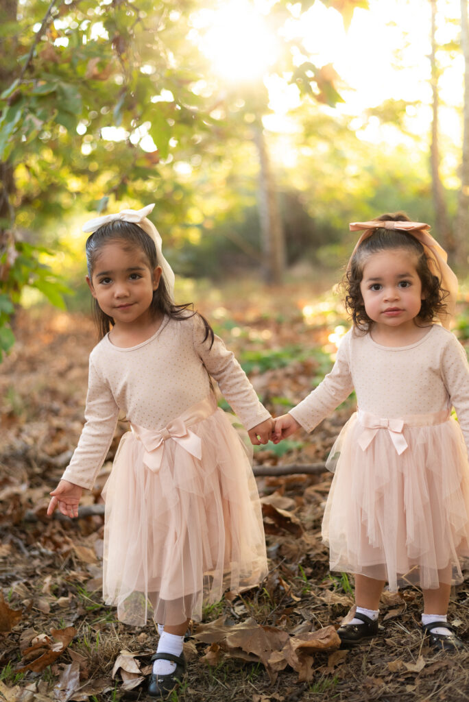Two toddler sisters hold hands during a family session in Fallbrook, CA