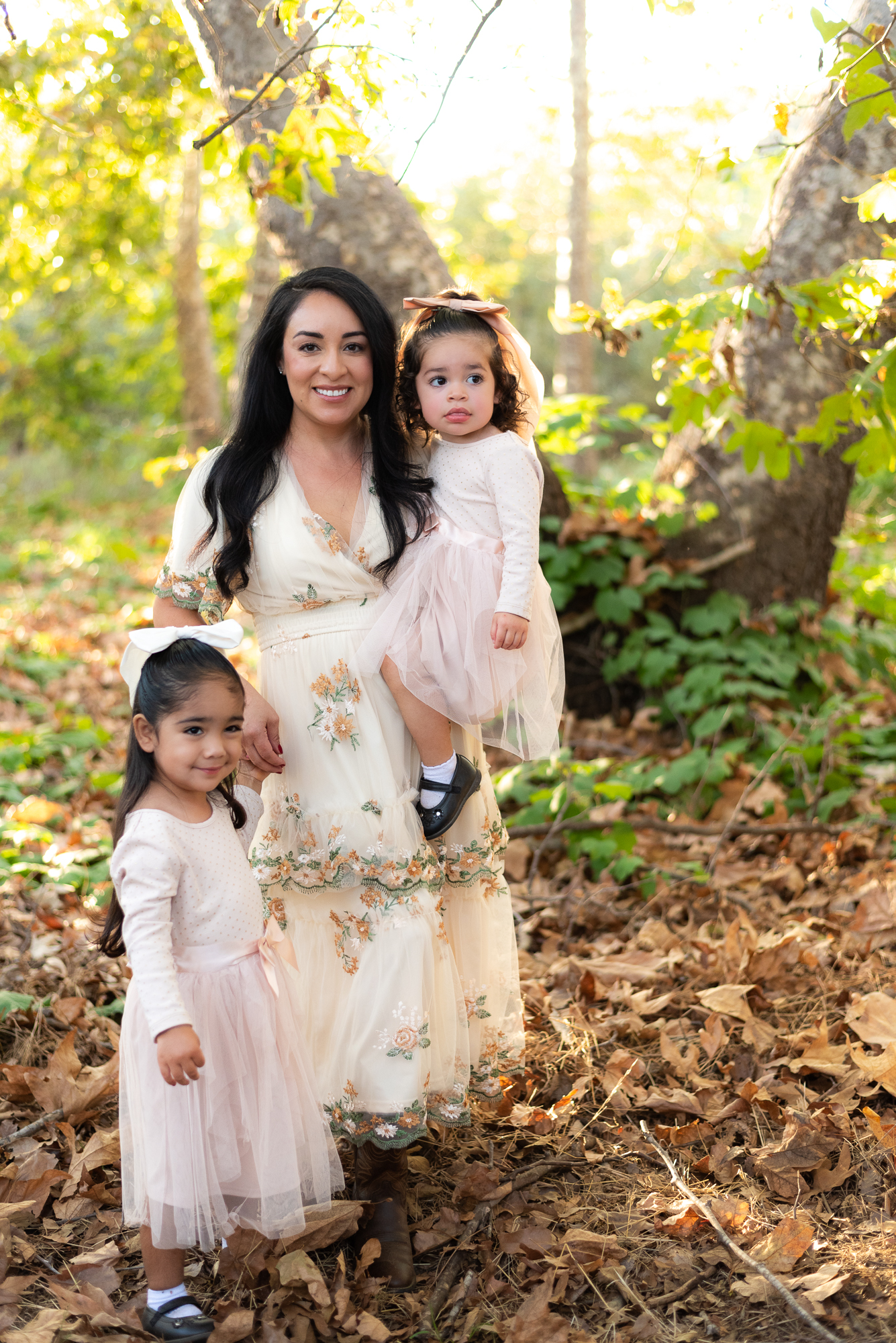 Mother and two young daughters pose in sunlit grove in Fallbrook, CA