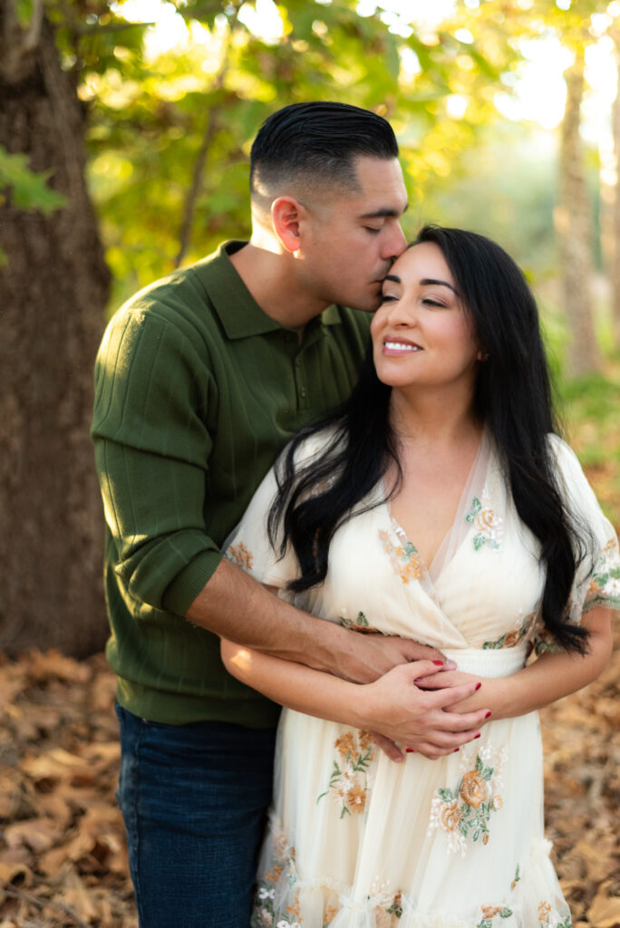 Couple shares a tender kiss in a sunlit grove in Fallbrook, CA