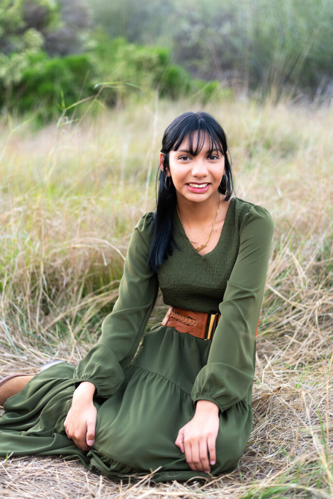 A teenage girl poses in a grassy meadow during a family session in Fallbrook, CA