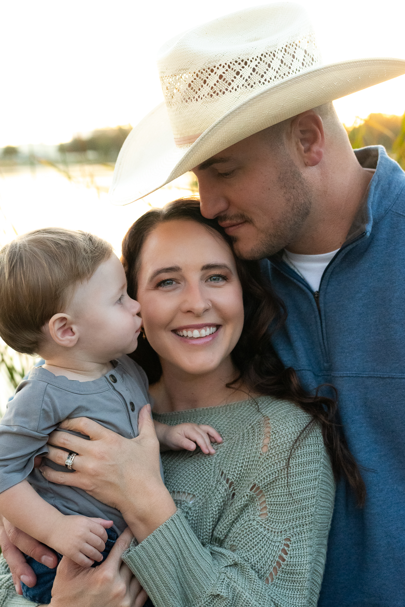 Family of three posing by a lake during golden hour family photos in Lodi CA
