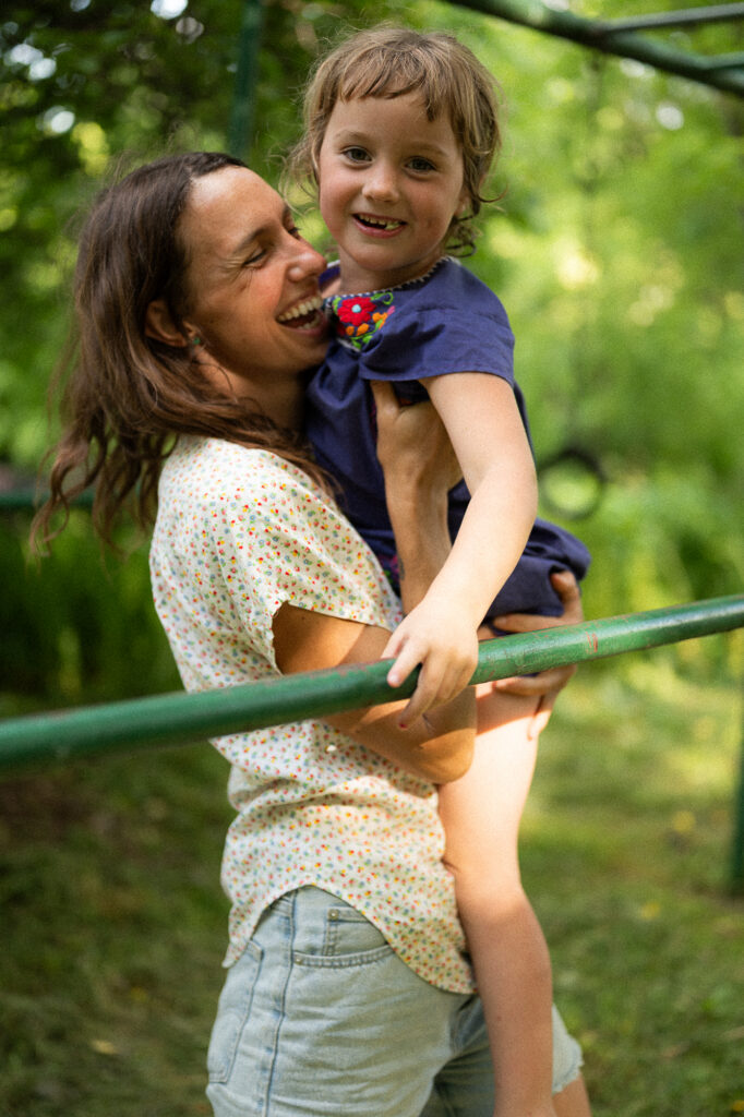 Mother holds up her daughter and laughs during a documentary family photography session