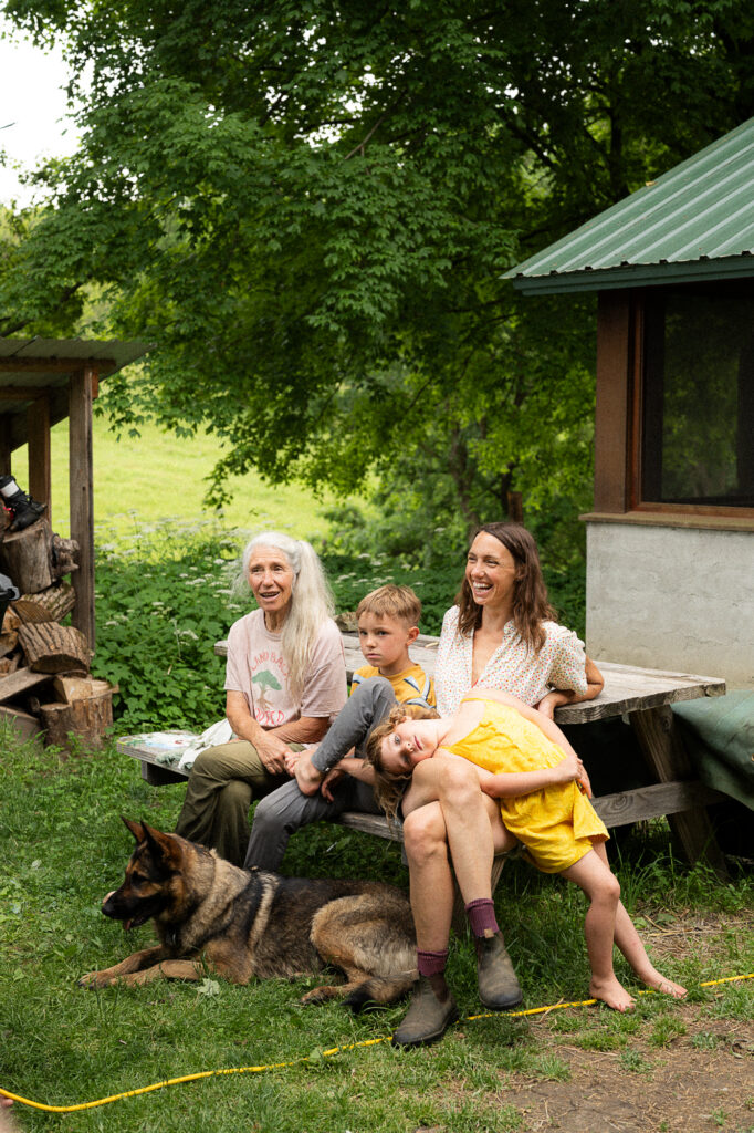Family sits with their kids and dog outside on a picnic bench during a documentary family photography session