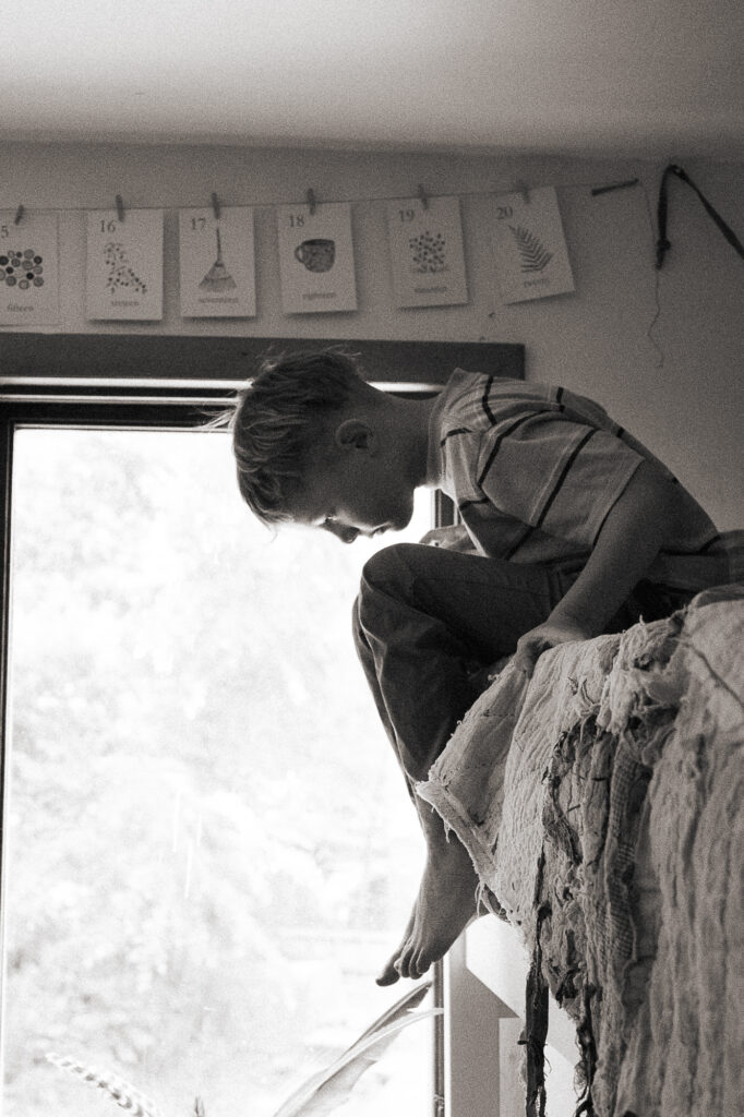Boy peers down over his bunk bed during a documentary family photography session