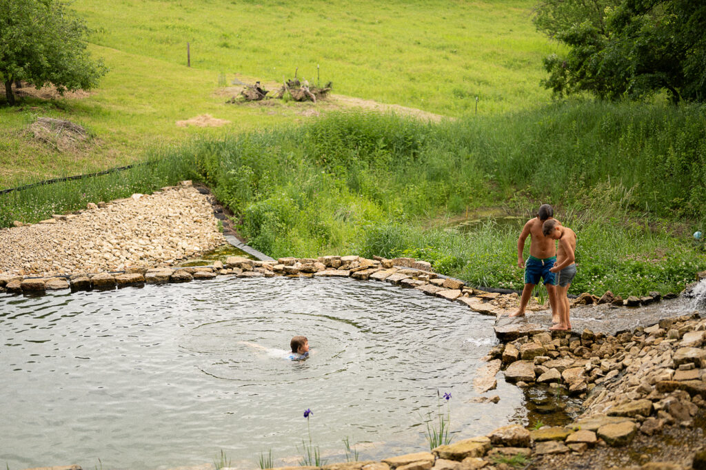 Kids swim in a natural rock lined pool during a documentary family photography session