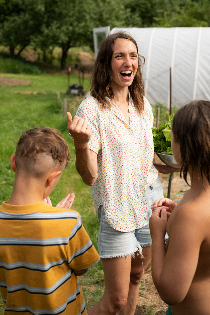 Mother laughs in her garden with her kids during a documentary family photography session